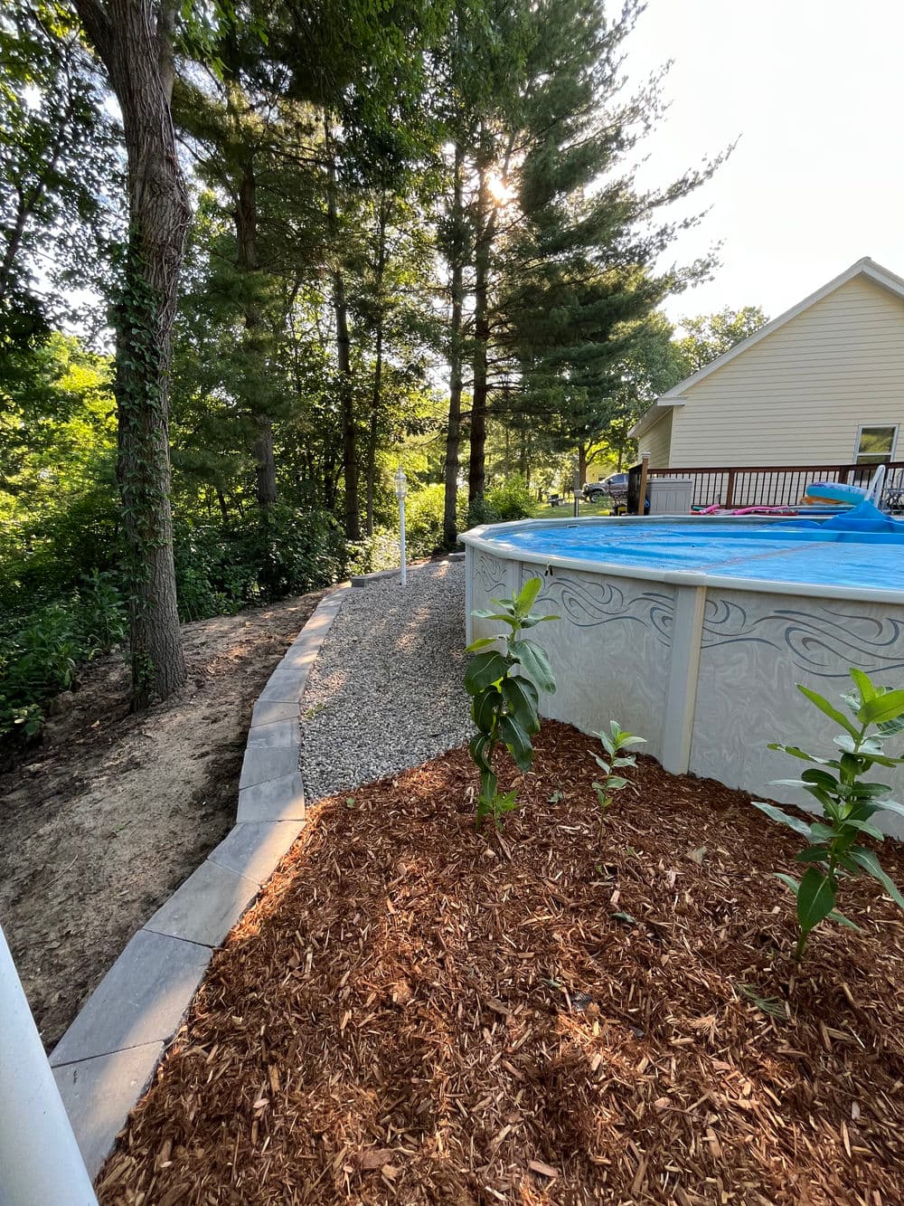 Poolside pathway surrounded by trees and landscaped garden features.