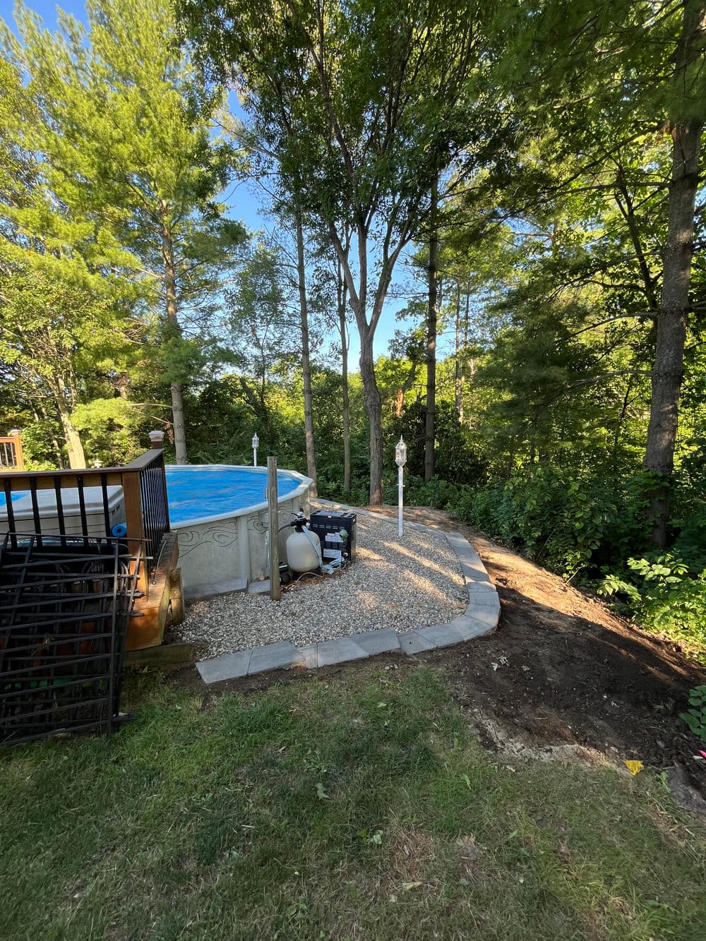 Backyard pool area with landscaping, trees, and equipment near the pool.