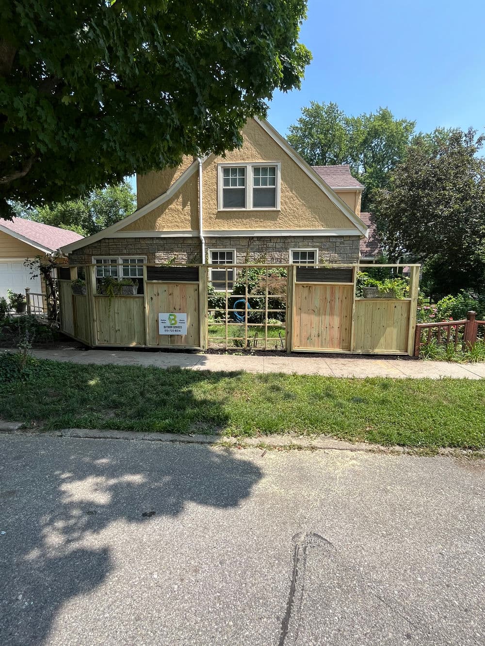 Charming house with a wooden fence and lush garden on a sunny day.