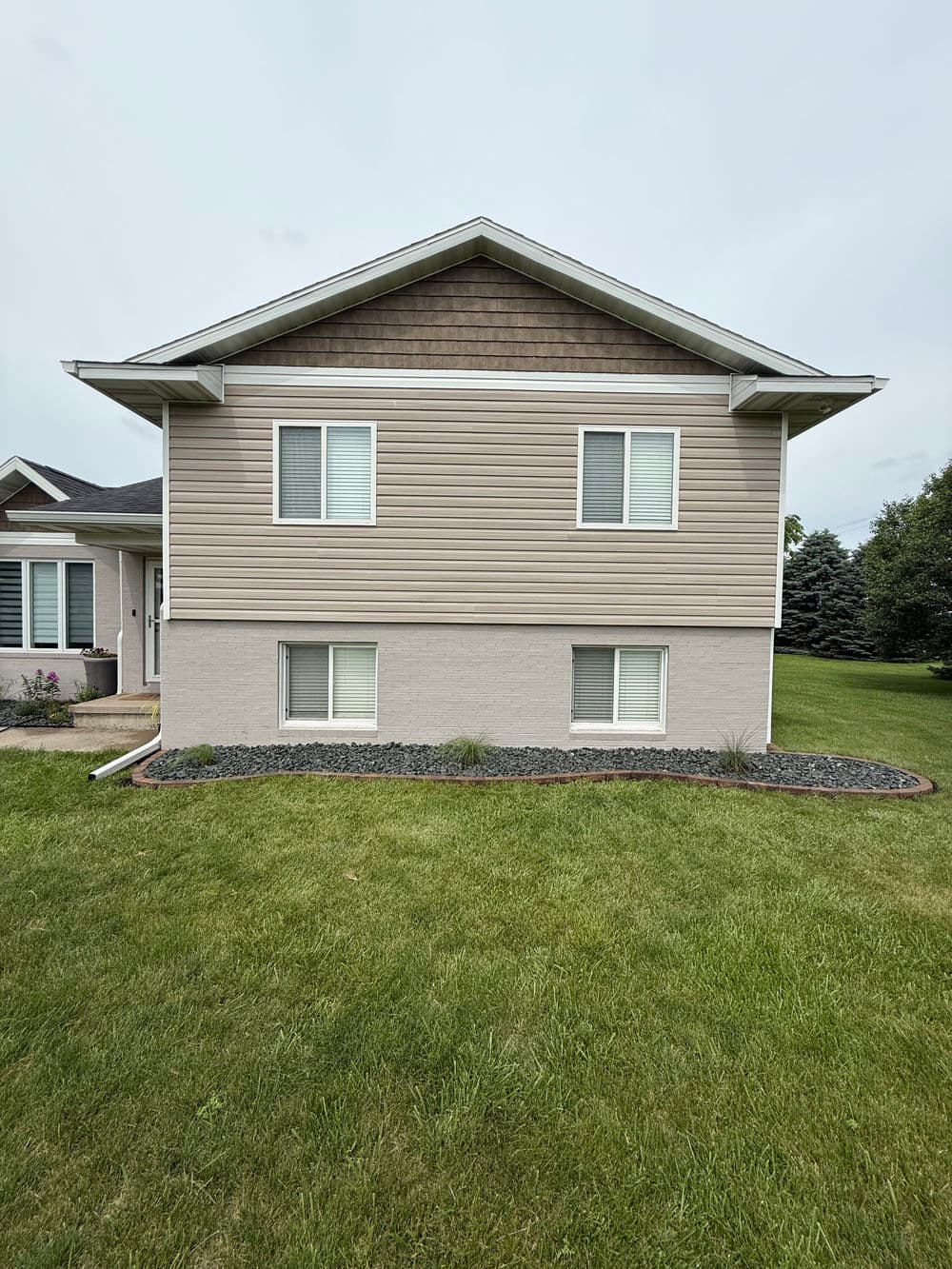 Modern two-story house with light brown siding and well-maintained green lawn.