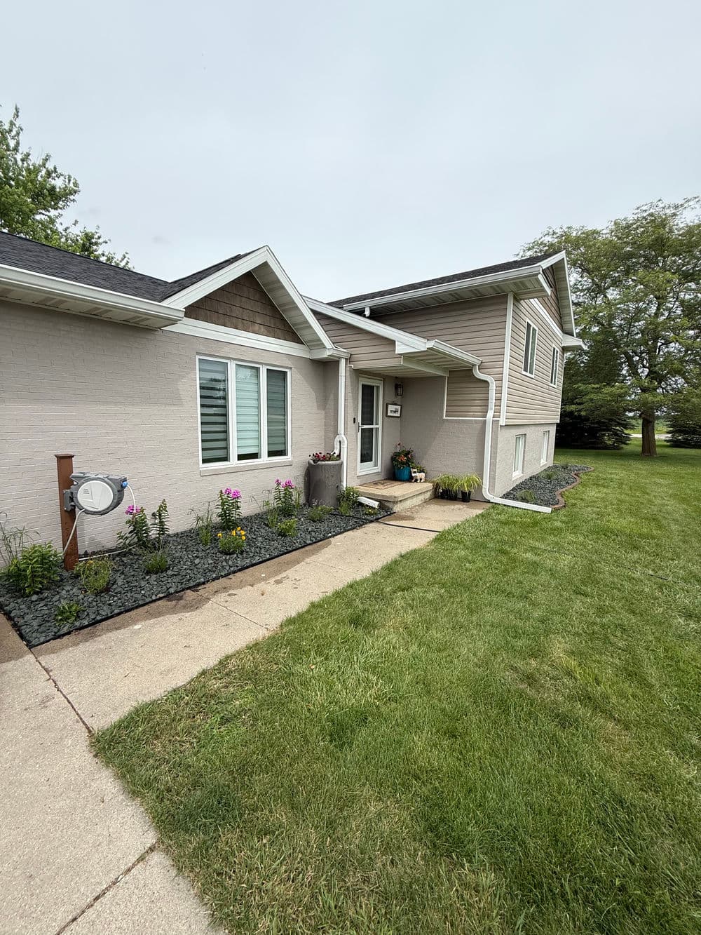 Modern suburban home with garden, grey siding, and well-maintained lawn.