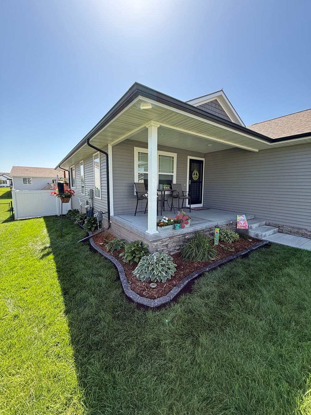 Modern home exterior with a welcoming porch, vibrant landscaping, and sunny garden space.