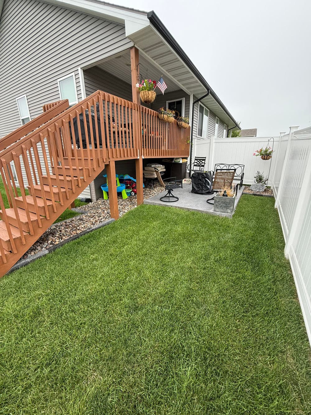 Backyard patio with seating area, stairs, and greenery in a residential setting.