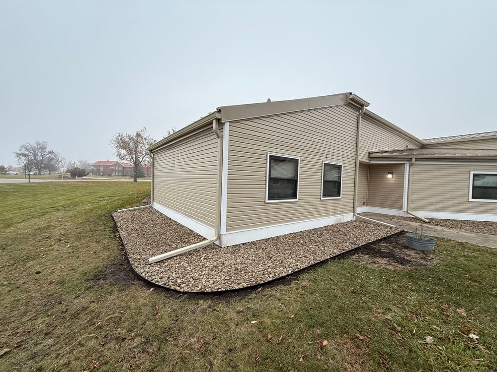 Modern home exterior with beige siding and gravel landscaping on a foggy day.