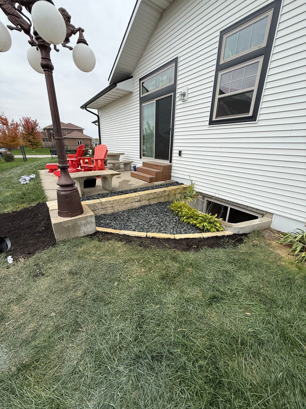 Landscaped patio with steps, greenery, and outdoor seating next to a house.